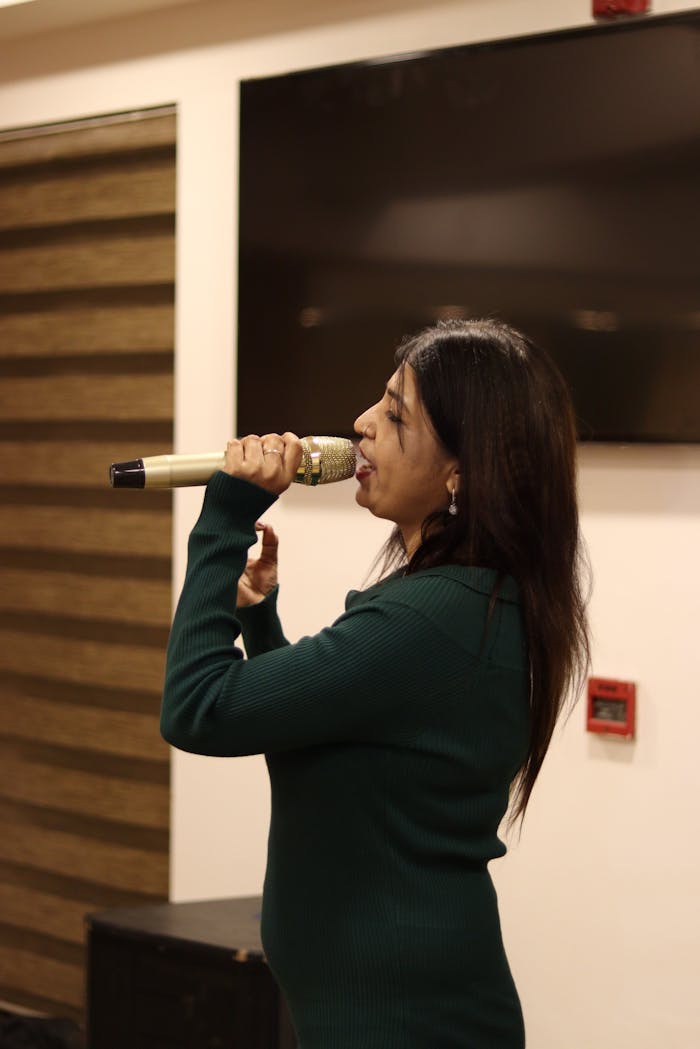 Woman passionately singing with a microphone indoors, perfect for entertainment themes.