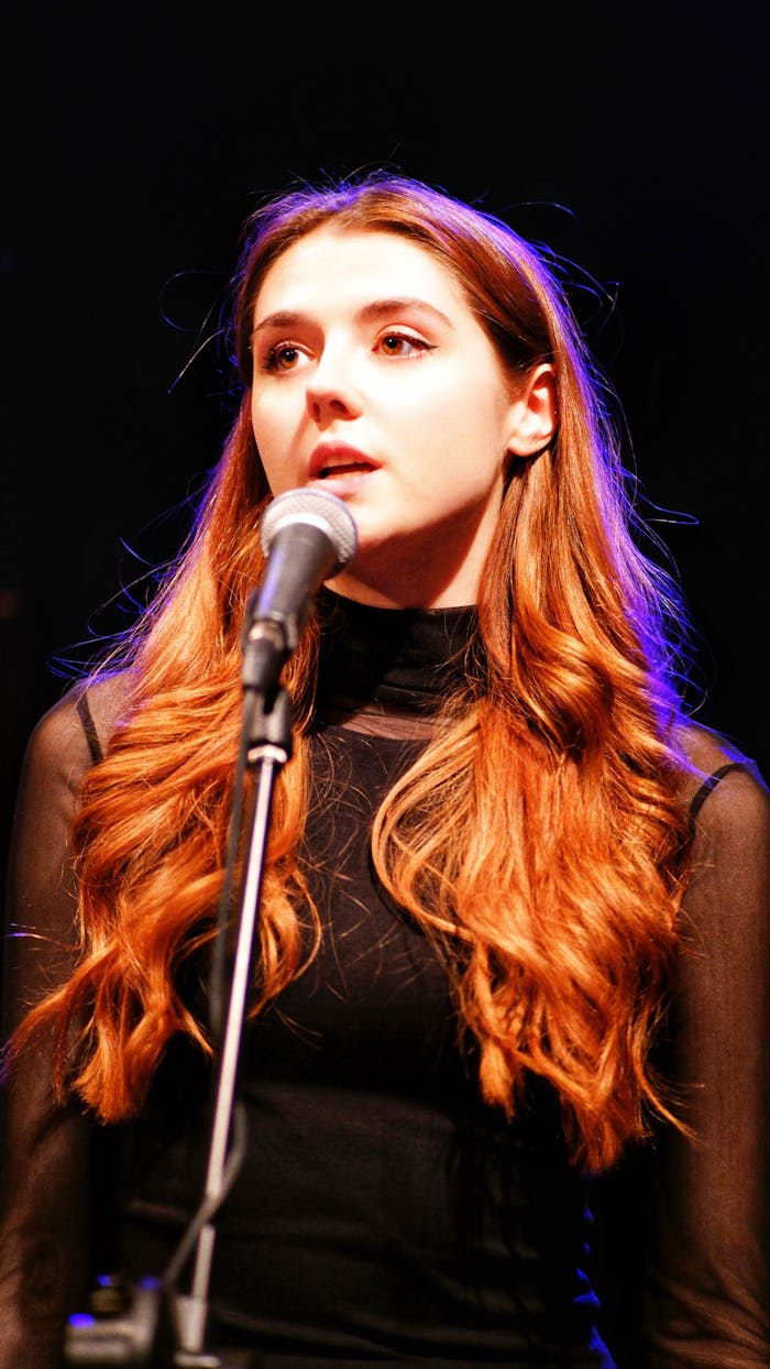 Energetic young woman singing passionately into a microphone on stage.